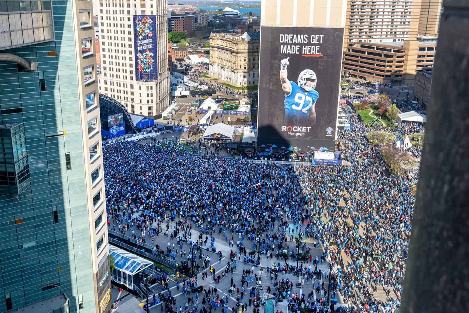 View from high above of large crowd gathered in downtown surrounded by tall builidings.