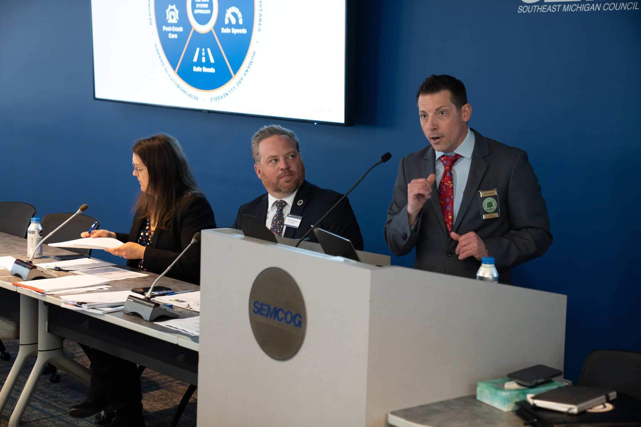 two people sitting next to speaker, standing at podium