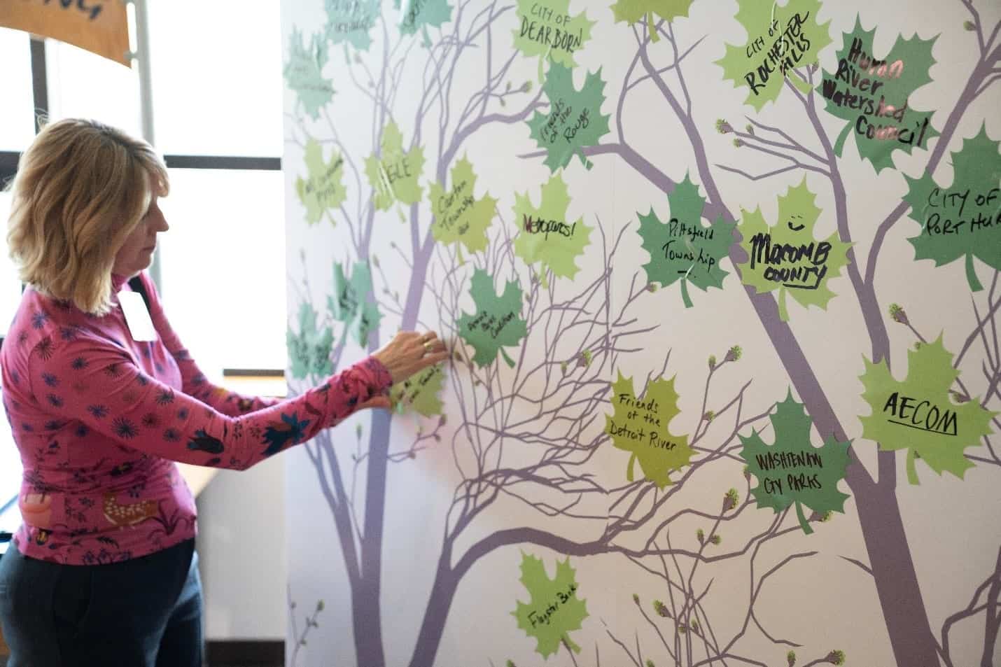 One person standing, facing tree banner