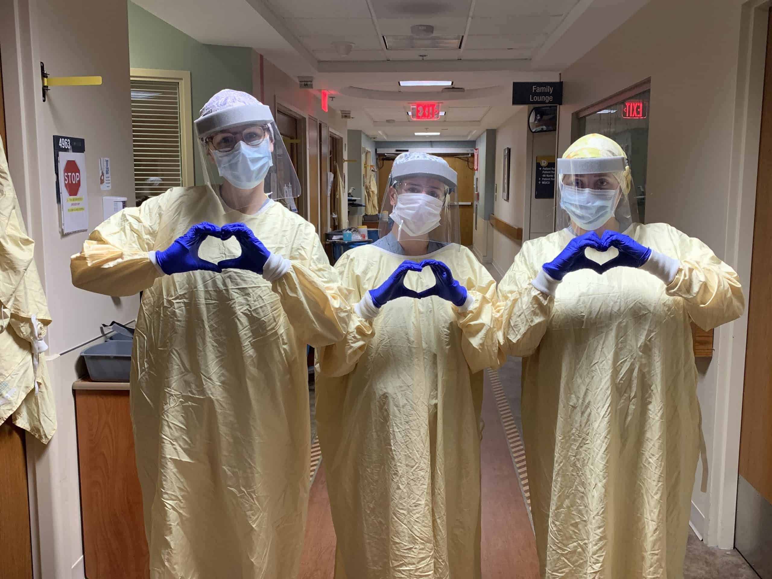 Nurses wearing personal protective equipment holding their hands in heart shapes