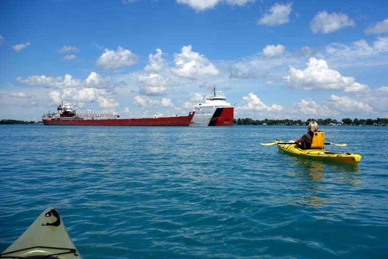 sunny day with two kayakers on water and with freight in the distance