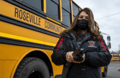 Woman with mask in front of Roseville Community school bus
