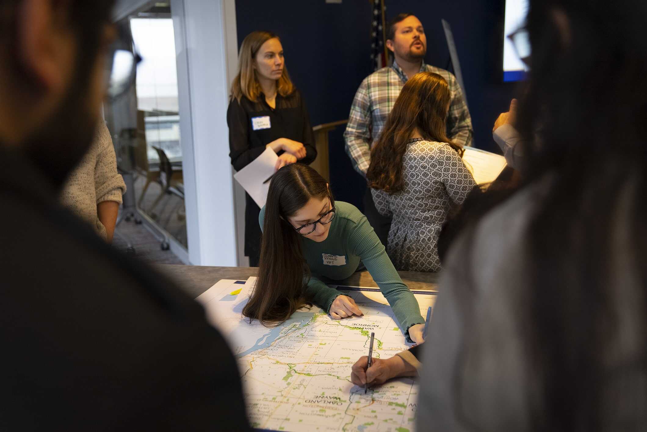 Two Summit attendees collaborating with map with surrounding group