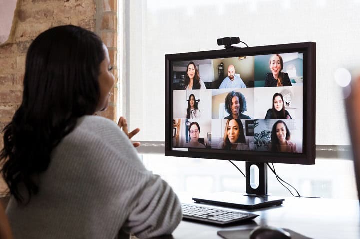 A woman talks to colleagues on her computer during a virtual meeting