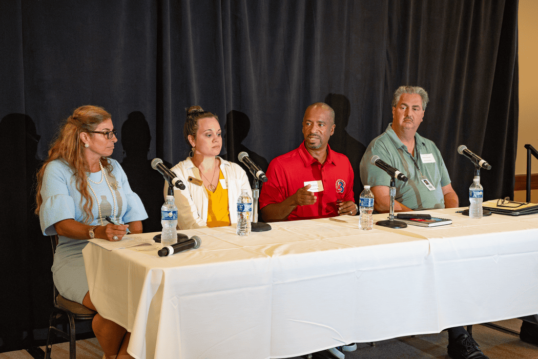 four people sitting at table with microphones