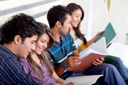 Four students sitting next to each other reading
