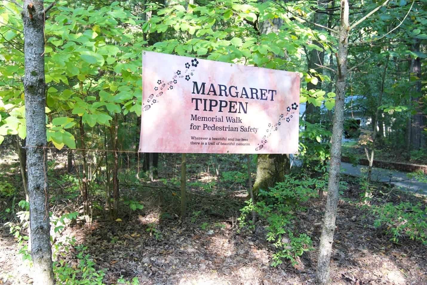 Banner hanging in trees, Margaret Tippen, memorial walk for pedestrian safety. Wherever a beautiful and has been there is trail of beautiful memories.