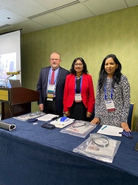 Three people standing and smiling at conference table