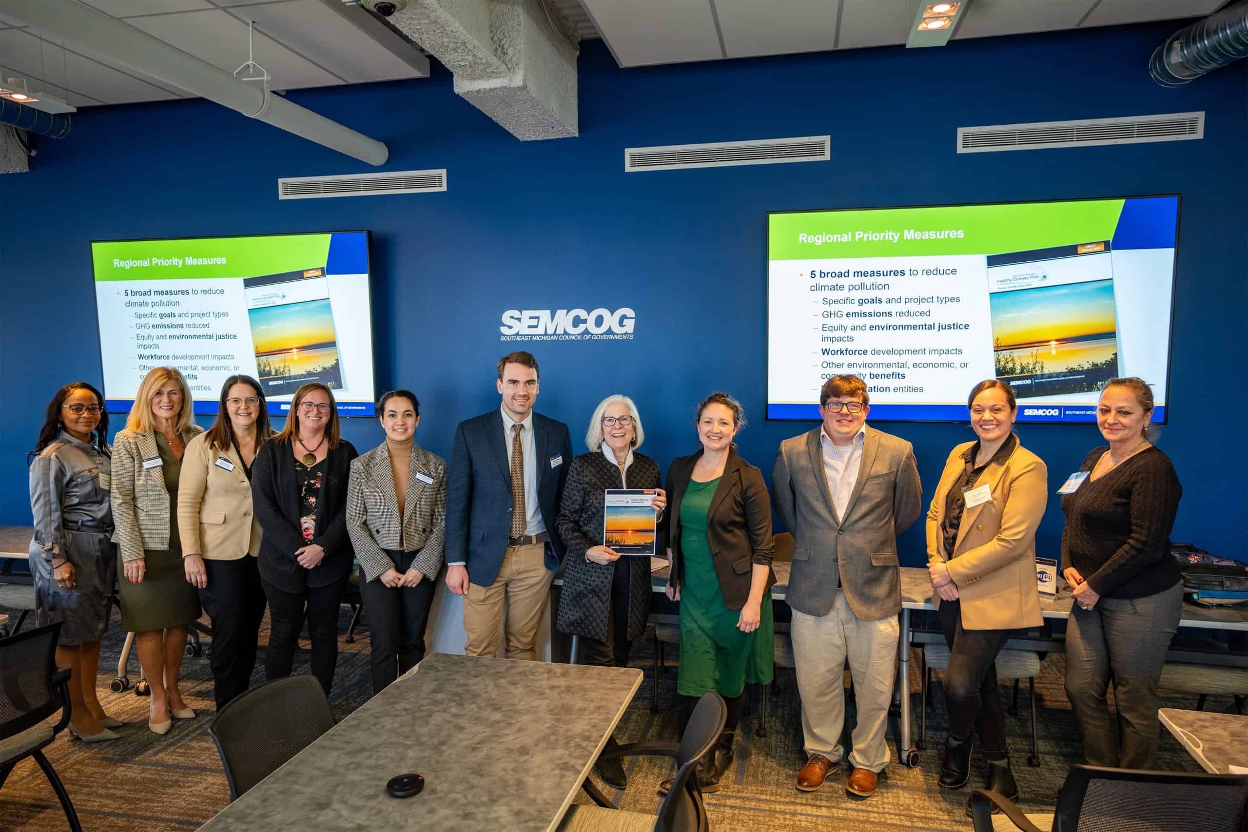 Group of people standing in front of a presentation, smiling