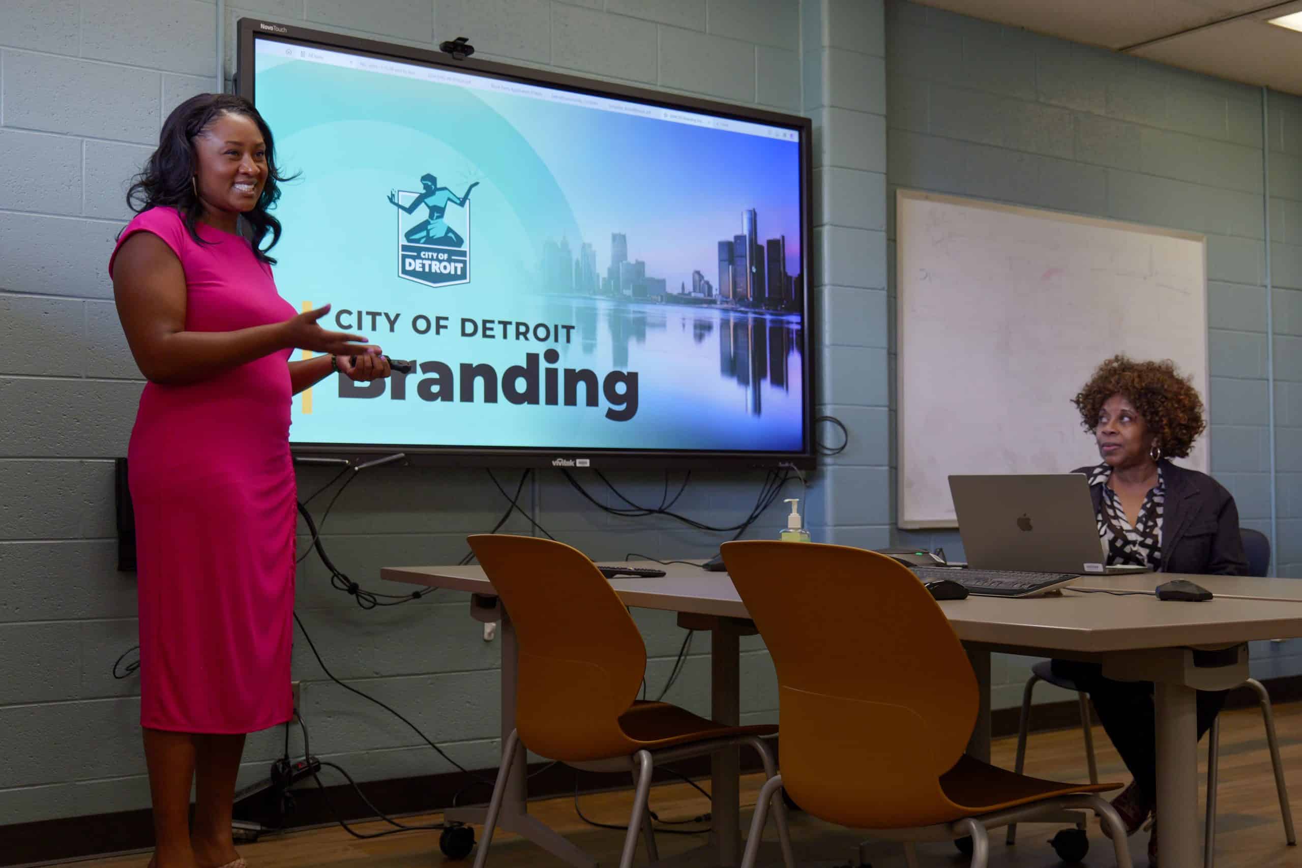 Presenter smiling and standing in front of city of detroit branding presentation