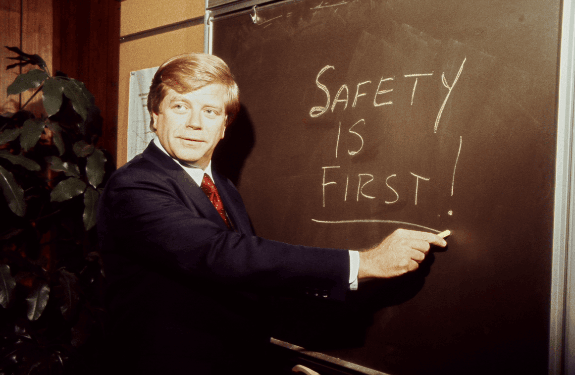 Man in a suit underlining safety is first! on a chalkboard