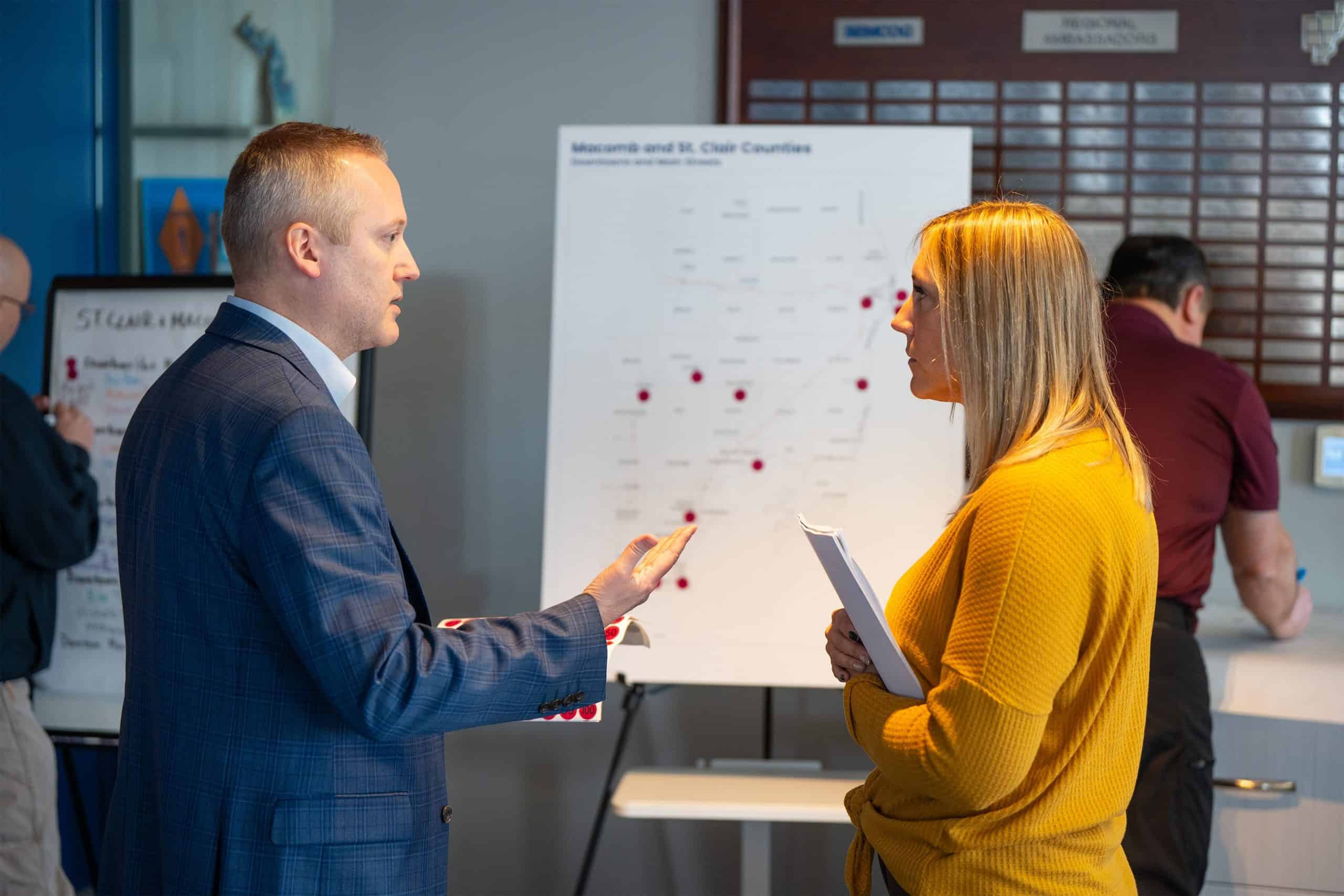 Two people speaking with each other in front of a brainstorming session