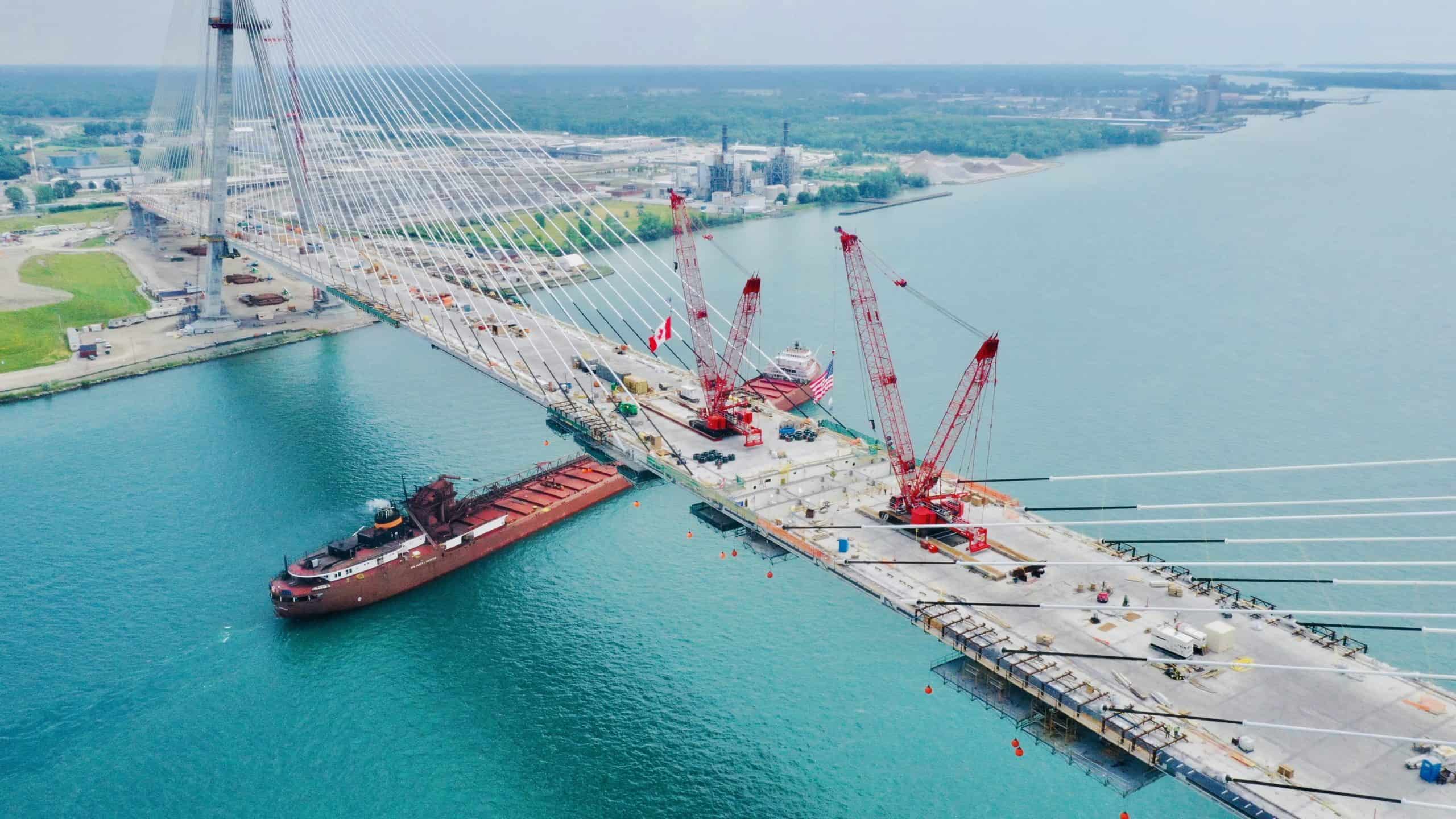 freight ship passing under construction of bridge