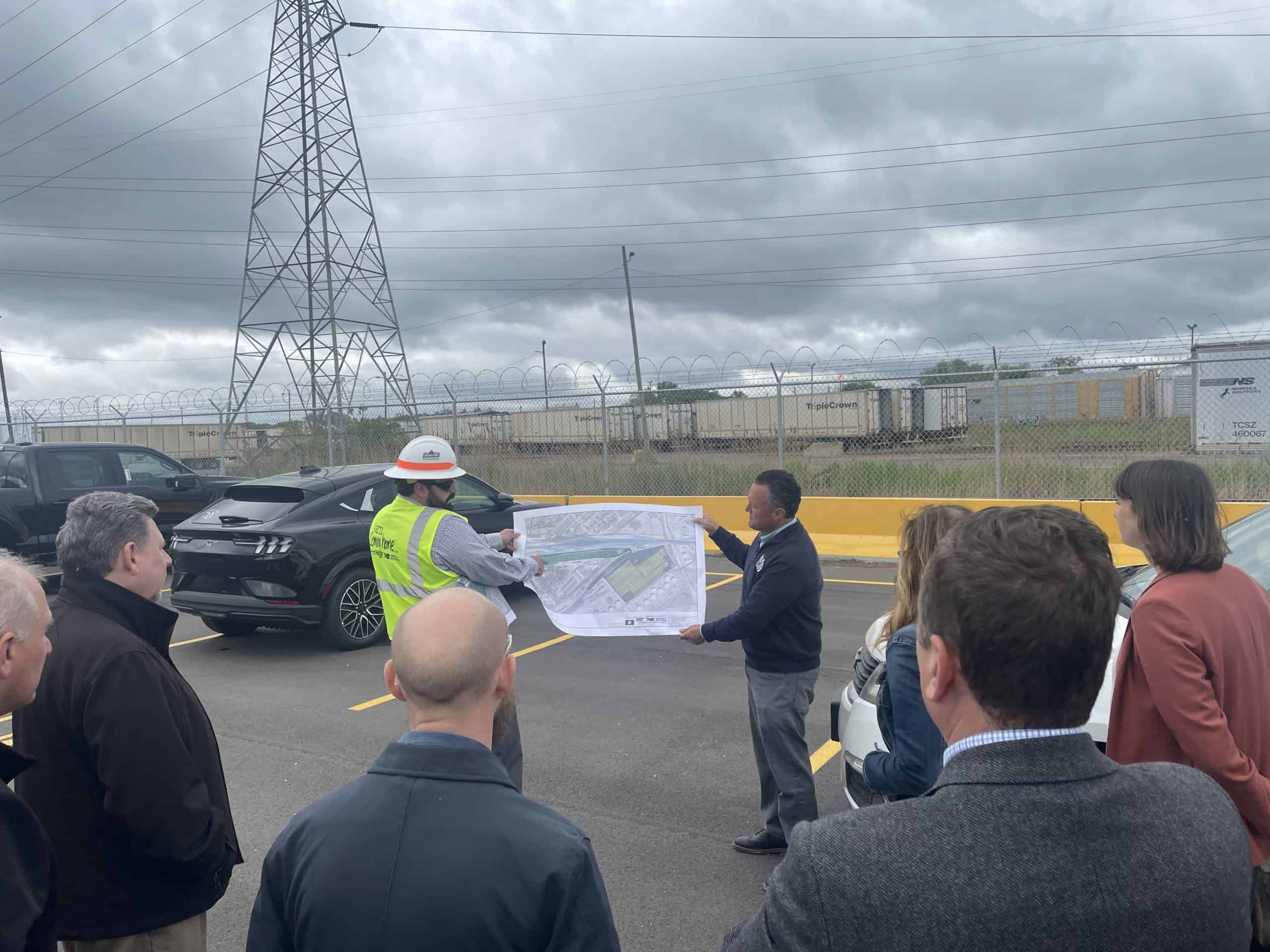 Engineers and city officials reviewing a construction plan at a transportation project site.