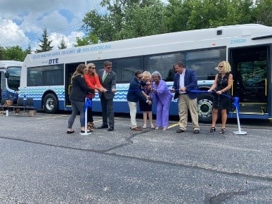 Ribbon cutting in front of bus
