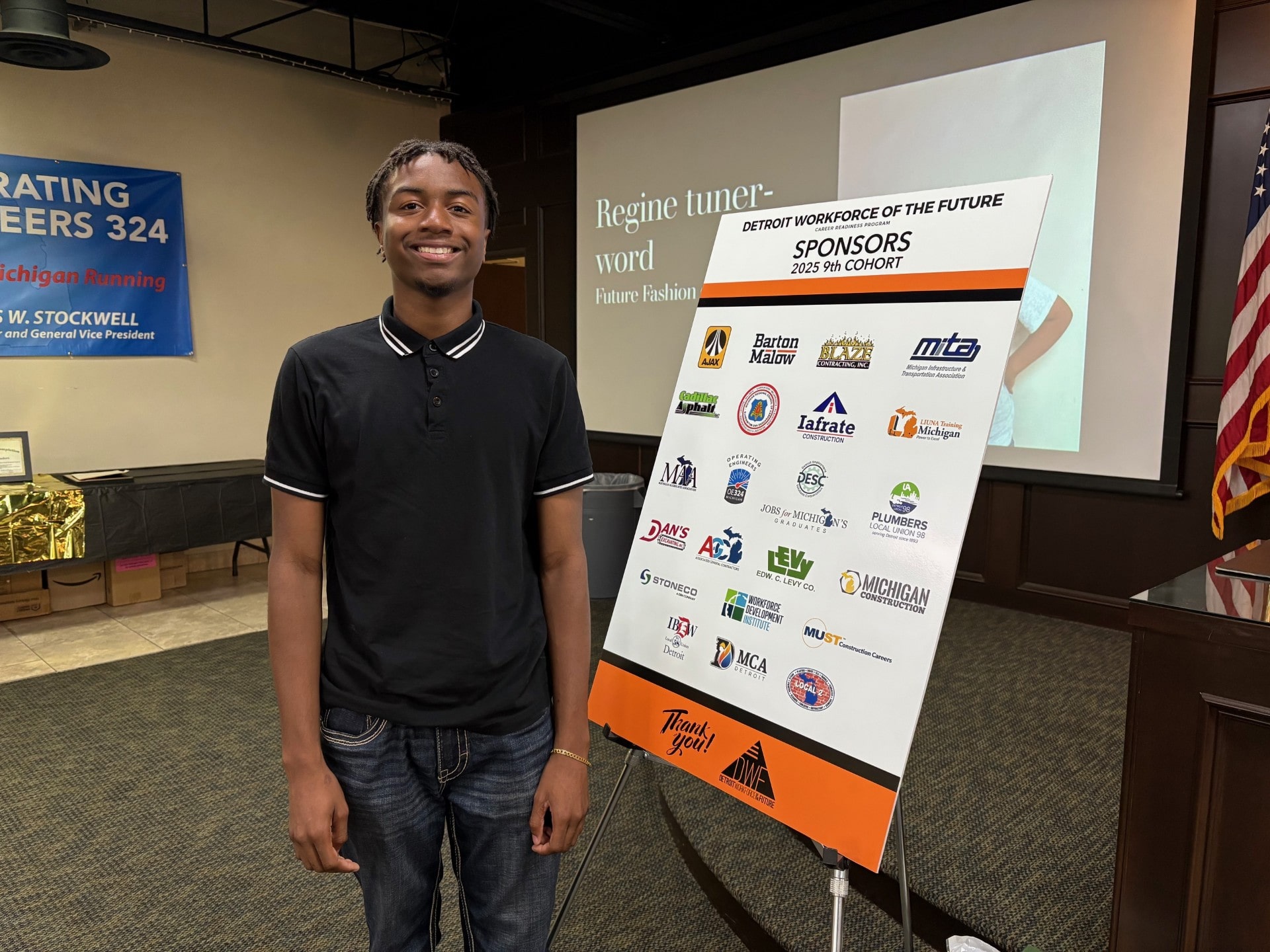 Graduate student standing next to poster with sponsors