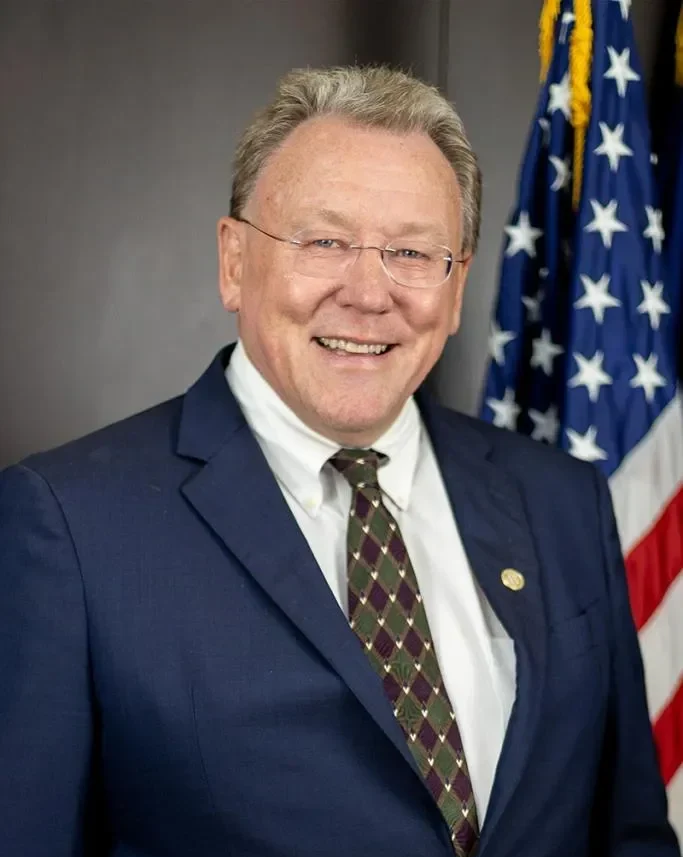 Don Brown, Deputy Commissioner for Macomb County Public Works and co-chair of SEMCOG’s Flooding Task Force, posing in front of a SEMCOG-branded backdrop, wearing a suit and smiling warmly.
