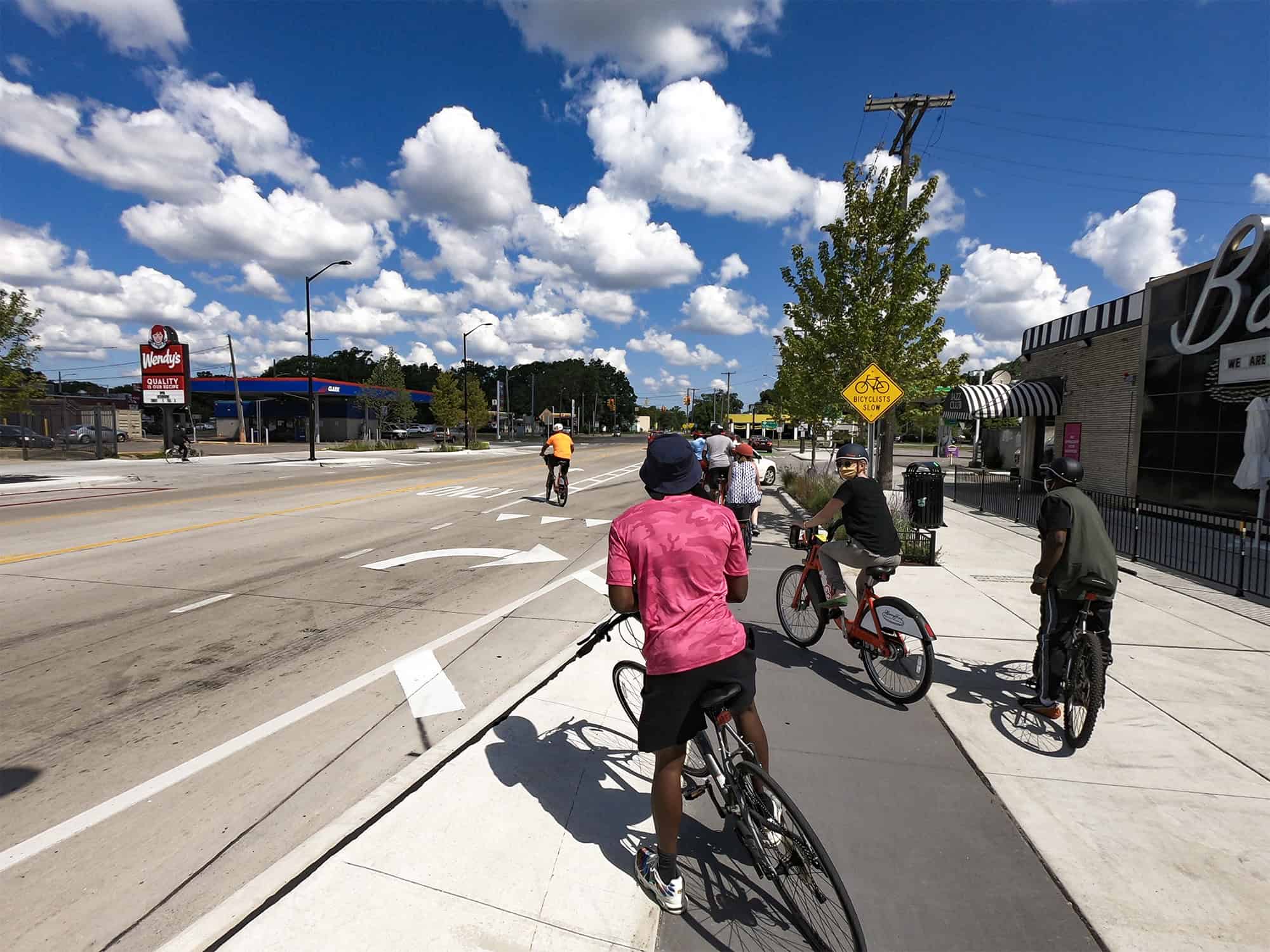 A newly painted bike lane on Livernois Avenue in Detroit, featuring green pavement markings, protective bollards, and clear signage to improve cyclist safety.