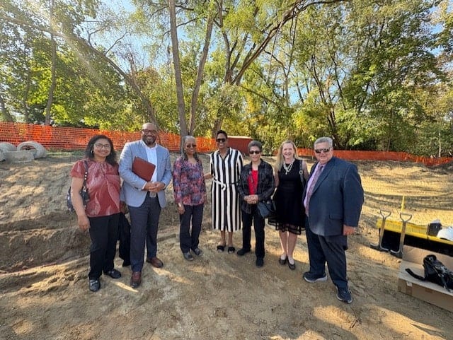 seven people standing together, outdoors at a ground breaking dig/construction site