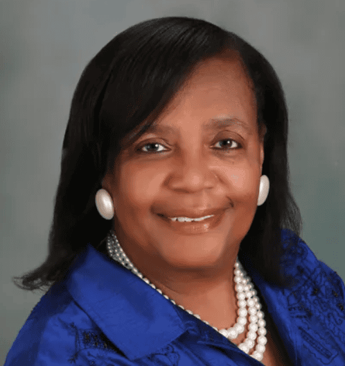 Portrait of Valerie Kindle smiling, with a neutral background and professional attire.