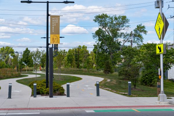 A walking/biking pathway with bike lane in front and trees in background
