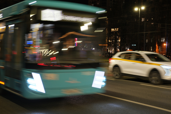 Blurred motion of blue bus and taxi on city street at night.