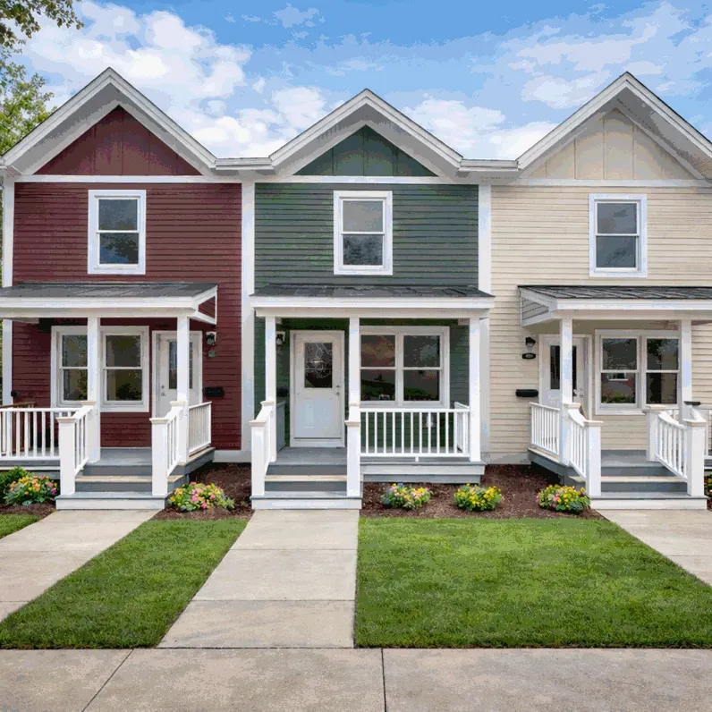 Three adjacent townhomes with red, green, and beige siding, front porches, steps, small gardens, and sidewalks in front.