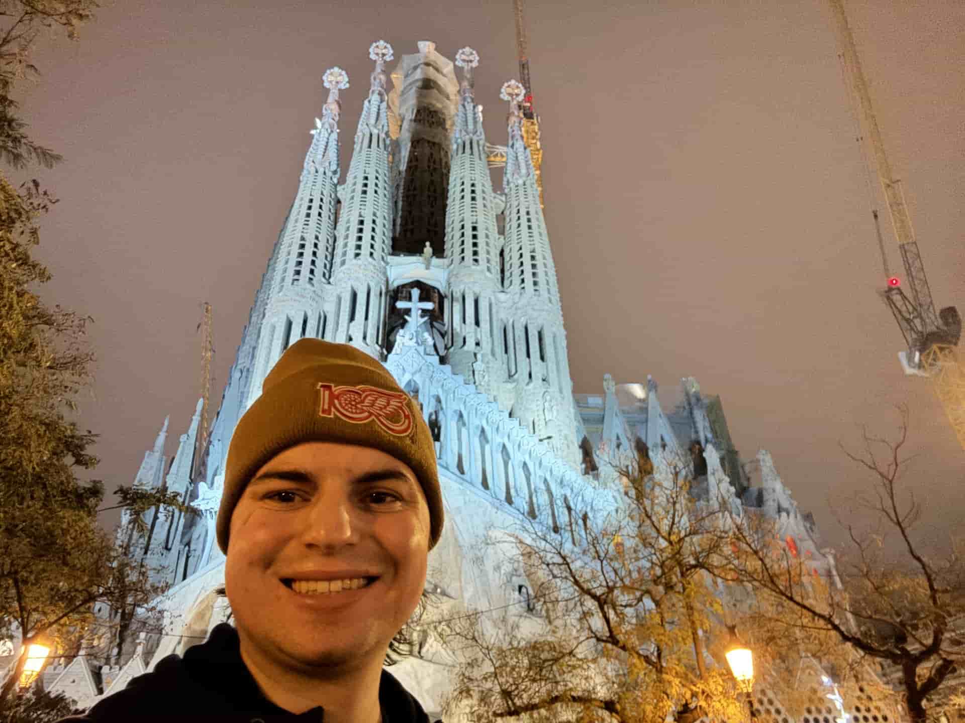 Person smiling in front of Basilica de la Sagrada Família at night