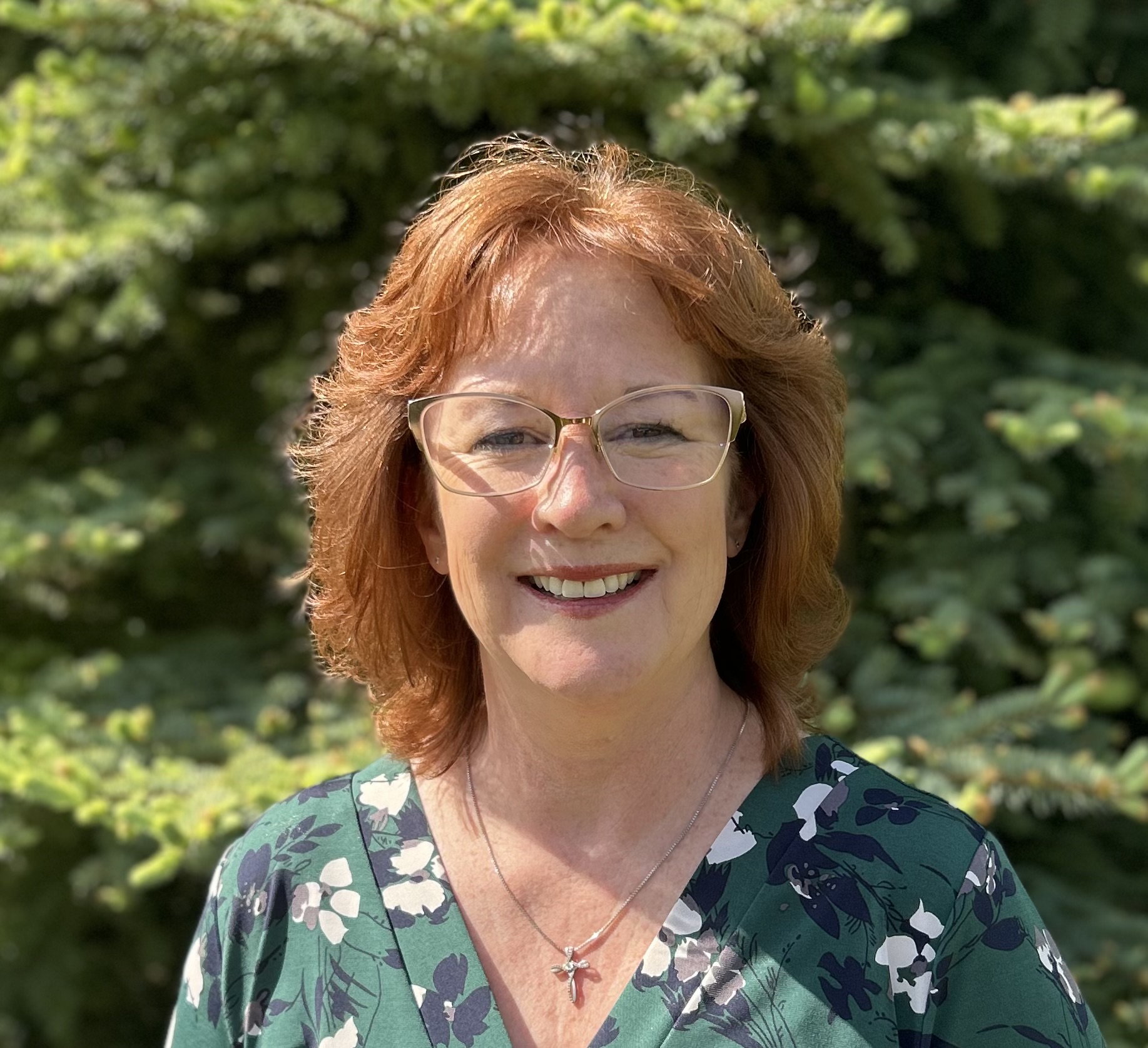 headshot photo of woman in front of trees