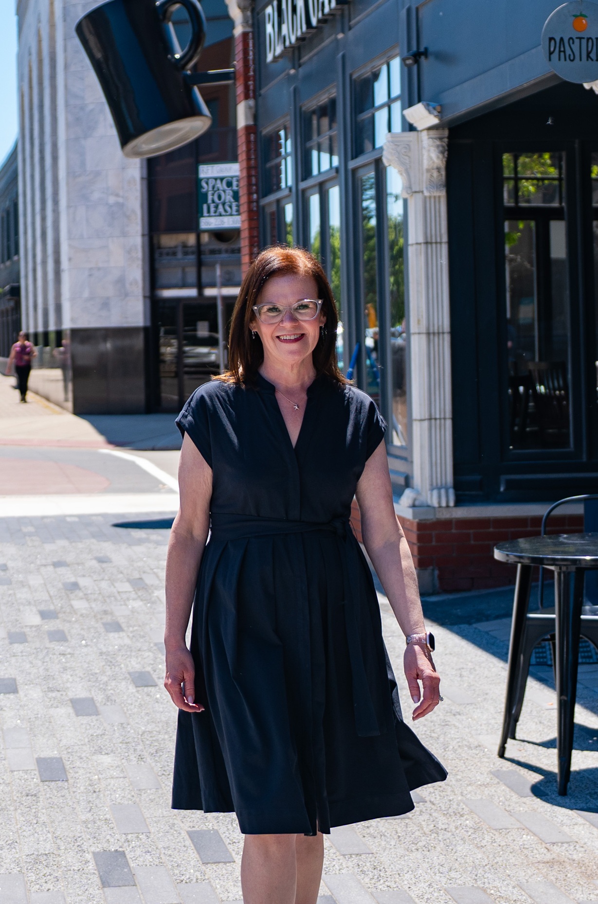 Woman walking in downtown area near building.
