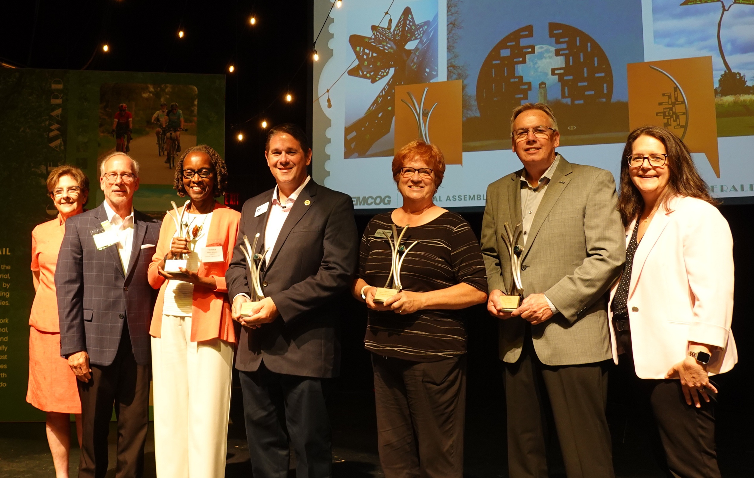 A group of people standing on stage and smiling while holding award trophies