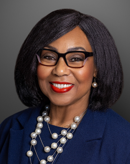 Headshot of Linnie Taylor in a navy blue top, pearl necklace and black eyeglasses