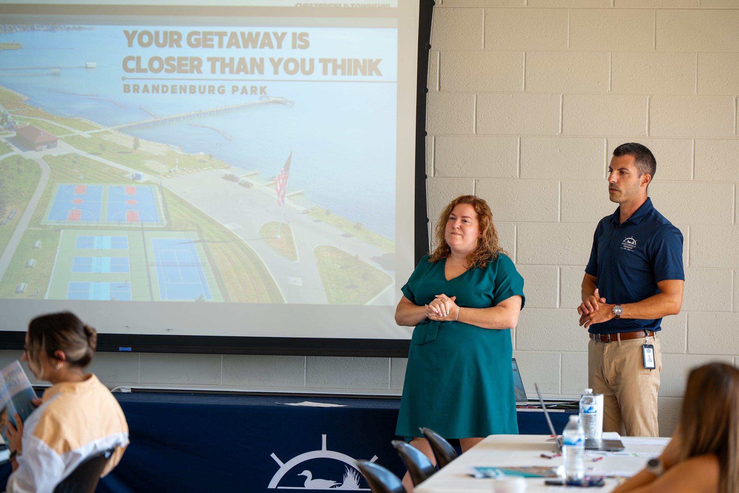 Speakers address a group during a community meeting featuring a presentation about Brandenburg Park.