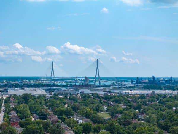 Aerial view of the Gordie Howe International Bridge spanning the Detroit River above neighborhoods and industry.