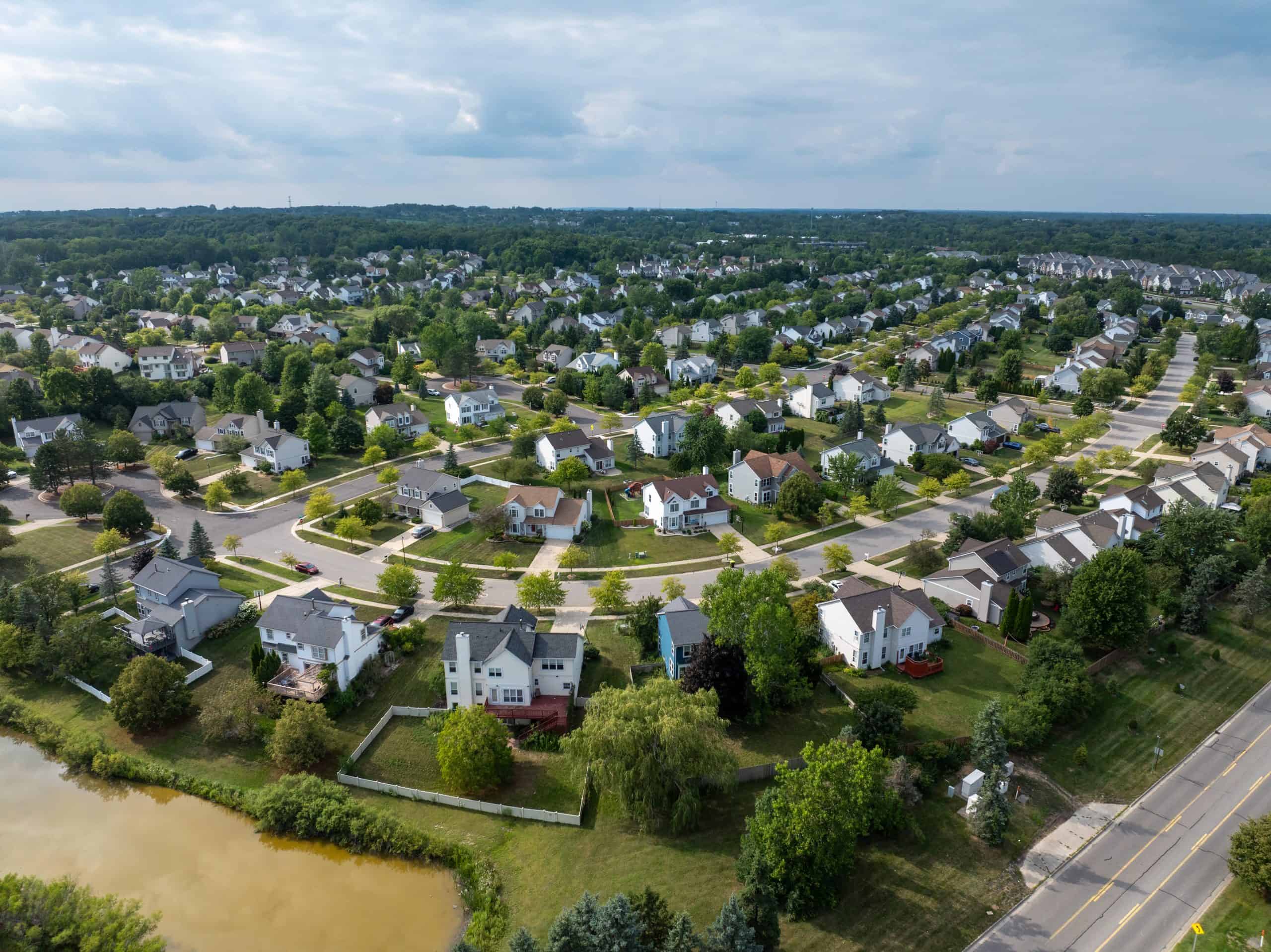 Aerial view of a suburban neighborhood with homes, tree-lined streets, and open green space.